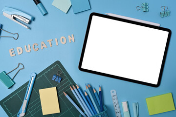 Mock up digital tablet with blank screen and various stationery on blue background. Back to school concept.