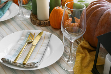 Beautiful table setting with fresh pumpkins and candles in room, closeup