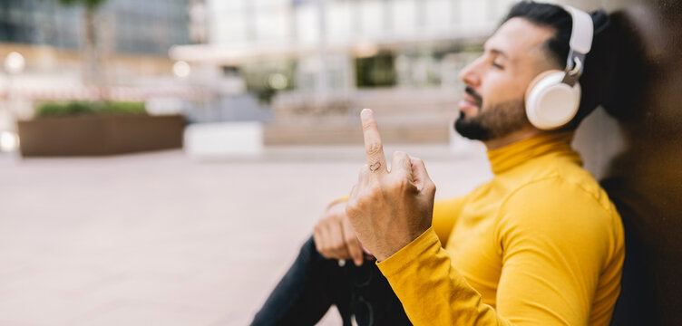 Man showing obscene gesture while leaning on wall