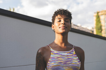 Short haired woman with eyes closed enjoying sunshine