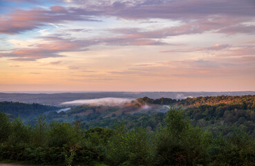 Low clouds and dramatic colours in the sky over the Devils Punch Bowl during sunset on the Surrey Hills near Hindhead south east England