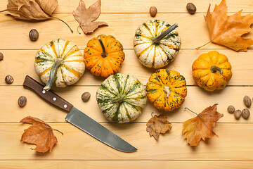 Ripe pumpkins, leaves, nutmeg and knife on wooden background