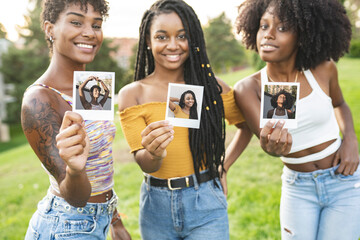Smiling young women showing photographs at park