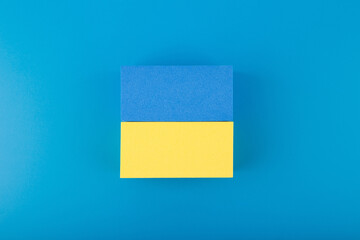 Creative flat lay with national flag of Ukraine made of toy rectangles on dark blue background with gradient. 