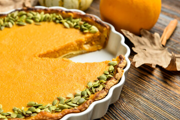 Baking dish with delicious pumpkin pie on wooden background