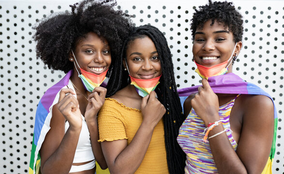 Smiling lesbian women wearing rainbow flag protective face masks
