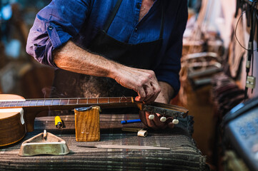 Luthier adjusting strings of guitar in workshop