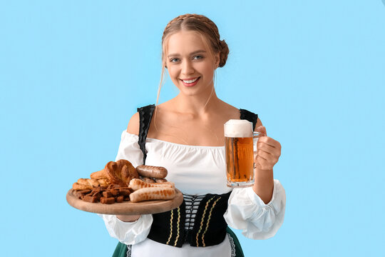 Beautiful woman in traditional German costume, with snacks and mug of beer on color background