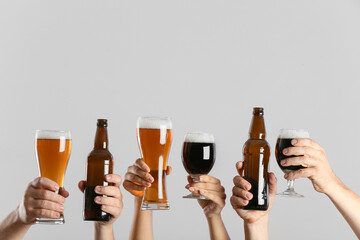 Hands with beer on grey background