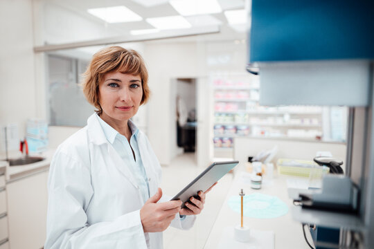 Female professional holding digital tablet while standing at laboratory
