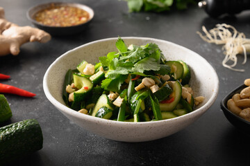 Chinese spicy broken cucumbers salad with cilantro, ginger, pepper chili, black vinegar on Asian cuisine. Spicy cucumbers. Popular cold Chinese appetizer. Close up.