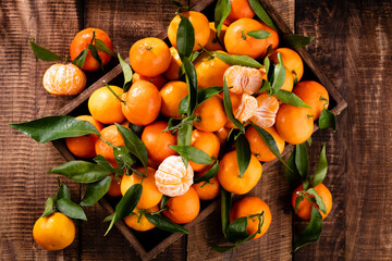 Fresh mandarin oranges fruit or tangerines with leaves in wooden box, top view