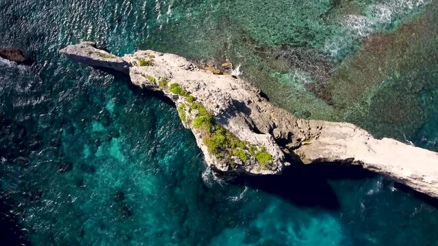 Top down view on rock cliff in ocean. High quality 4k aerial birds eye orbit footage