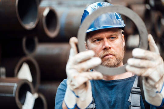 Male inspector checking circle shape steel equipment in warehouse