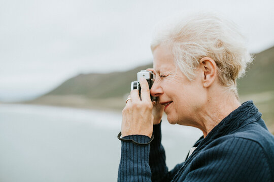 Senior woman capturing a picture of the ocean