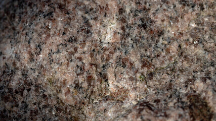 Red granite texture. A variegated, spotted background of red (brown) granite. The stone granite surface of brown-gray color. Surface view of granular igneous rock