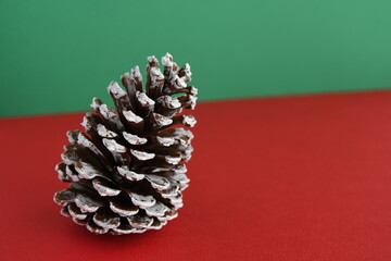 Christmas pinecone on red and green background.