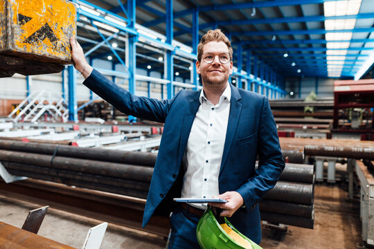 Male manager with hardhat standing at metal industry