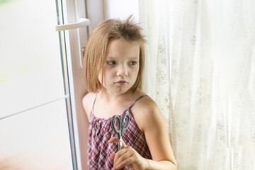 Emotional sad offended Caucasian girl child with scissors cuts off his hair, hooliganism and pranks child, child with funny oblique haircut, child cut off his hair - obrazy, fototapety, plakaty