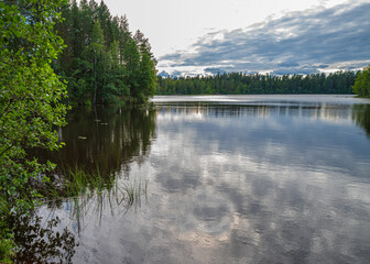 Fototapeta na wymiar Picturesque landscape of a forest lake with the reflection of clouds in the water.
