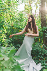 brunette girl Mavka Dryad Naiad forest nymph in a fairy tale in the forest among the trees in...