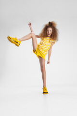 Portrait of little active Caucasian preschool girl posing at camera isolated over white background