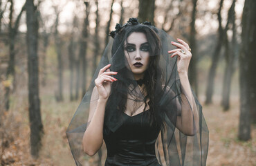 Brunette witch girl conjures in the forest conducts rituals with a fantasy skull nature magic in...