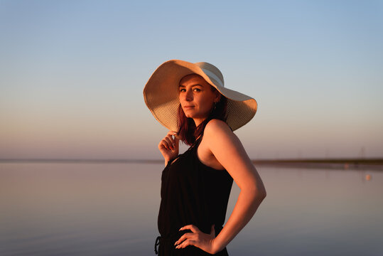 Portrait of young beautiful woman with a straw hat on nature background.
