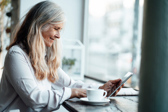 Female freelancer using digital tablet while sitting in cafe