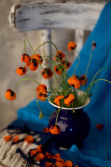 A Little Red Poppies Bouquet in blue vase on wintage chair