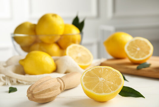 Wooden citrus reamer and fresh lemons on white table