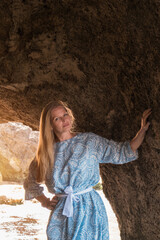 a woman on a rock looking into the distance against the sea