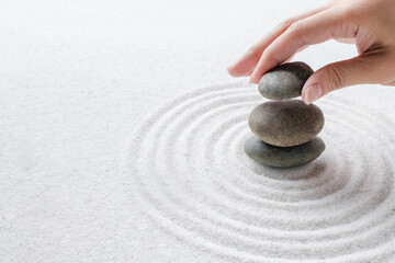 Fototapeta na wymiar Hand stacking zen stones on the sand wellness background