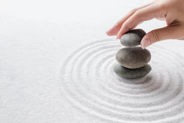 Foto auf Acrylglas Hand, die Zen-Steine auf dem Sand-Wellness-Hintergrund stapelt © Rawpixel.com