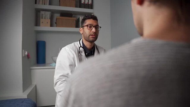Mixed race male doctor chatting to patient 