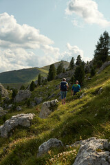 Wanderer und Wanderin wandern in den italienischen Dolomiten in Südtirol am Sella Joch am Nachmittag an satt grünen Hügeln