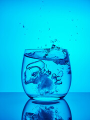 Creative splashing water in the glass on blue background. 