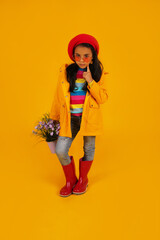 a dark-skinned girl in a red beret, pink heart-shaped glasses, a yellow raincoat, and a bucket with flowers in her hands