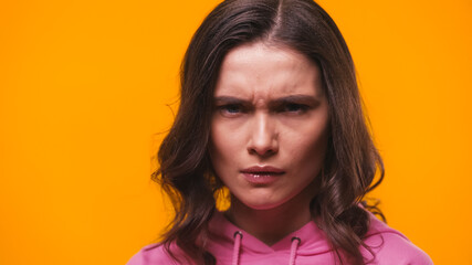 grumpy woman frowning while looking at camera isolated on yellow