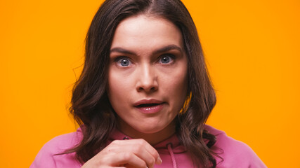 impressed brunette woman looking at camera isolated on yellow