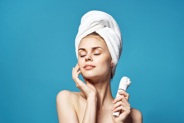 beautiful woman with a towel on her head massager in hands skin care