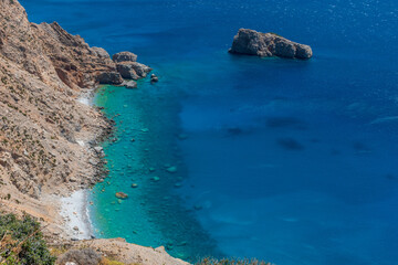 view of the turquise waters from the beach underneeth  the famous Hozoviotissa Monastery standing...