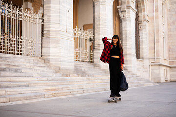 Portrait of young beautiful girl with skateboard. Happy smiling woman relaxing outdoors
