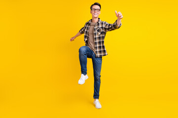 Fototapeta na wymiar Photo of inspired dreamy guy dance enjoy party wear plaid shirt jeans shoes isolated yellow color background