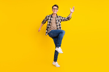 Fototapeta na wymiar Photo of carefree nice guy raise hand dance wear plaid shirt jeans footwear isolated yellow color background