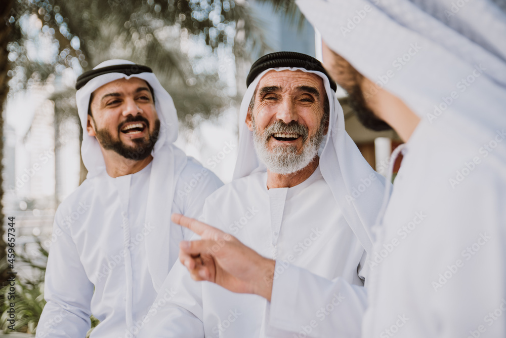 Wall mural three business men walking in dubai wearing traditional emirati clothes