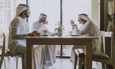 Three business men having a tea in Dubai wearing traditional emirati clothes