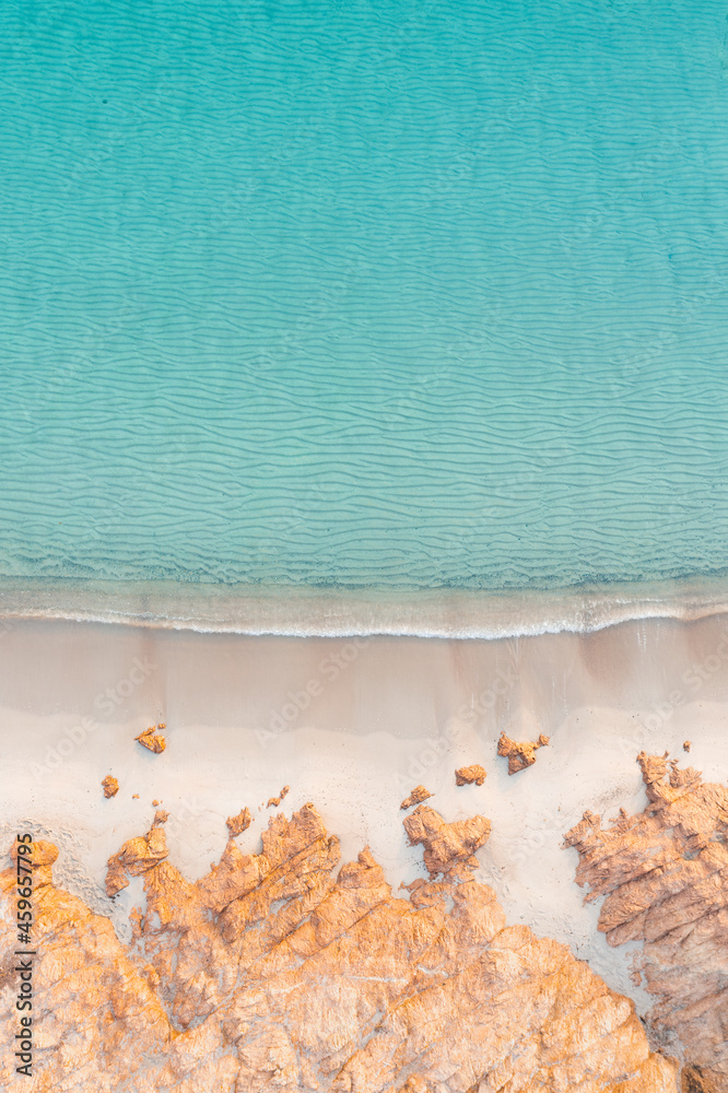 Poster view from above, stunning aerial view of a rocky coastline with a white sand beach bathed by a turqu - Posters