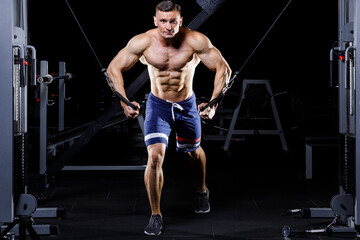 Fototapeta na wymiar Male handsome bodybuilder gaining muscles in the gym