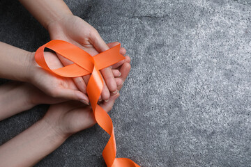 Couple holding orange ribbon on grey background, top view with space for text. Multiple sclerosis...